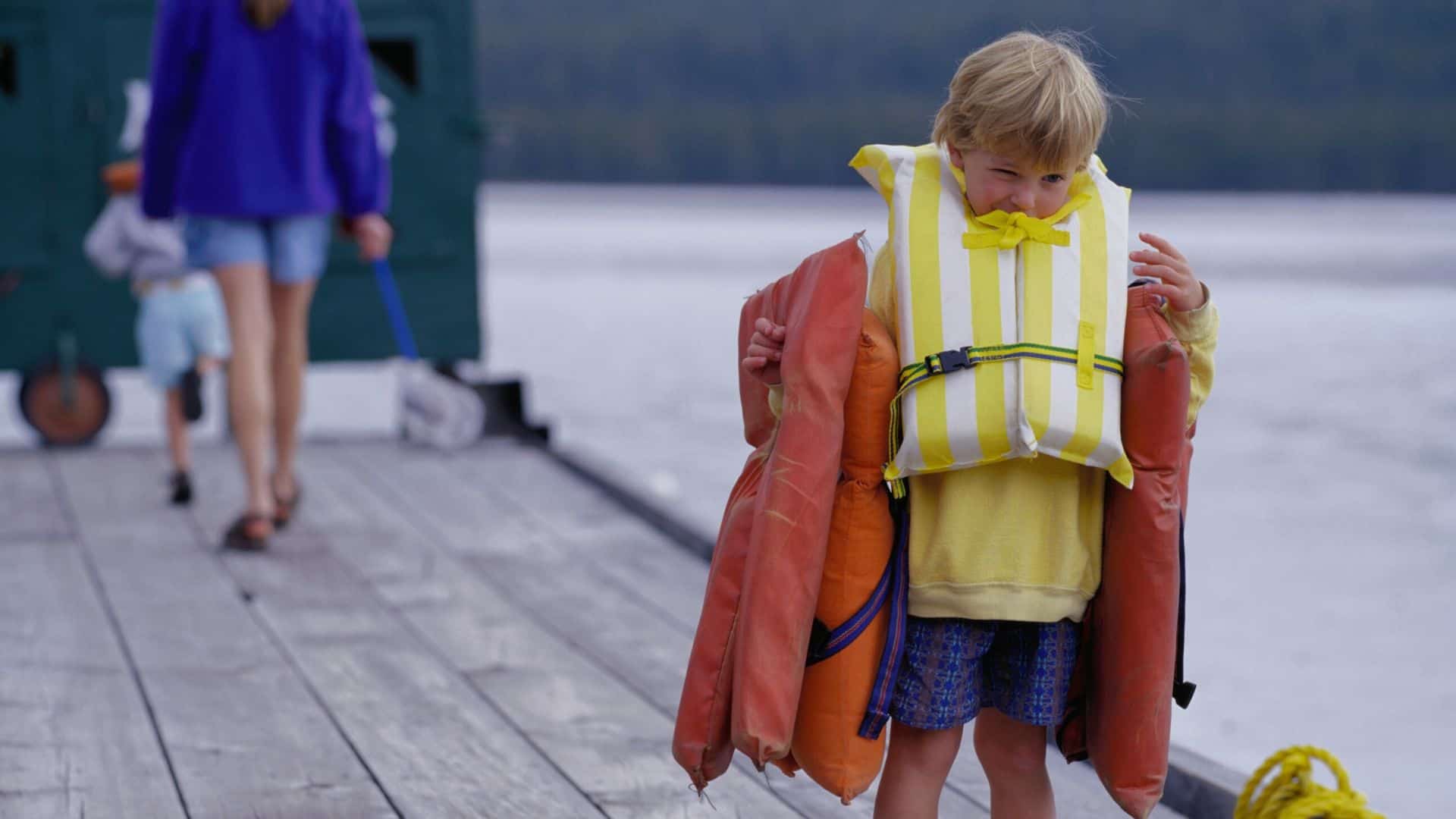 young boy carrying life jackets