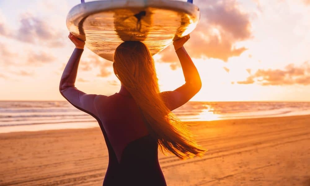 woman with surfboard at dawn